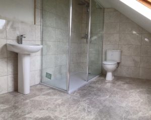 Shower, toilet and sink with floor and wall tiling